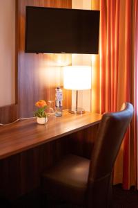 einen Schreibtisch mit einer Lampe und einem Stuhl in einem Zimmer in der Unterkunft Hotel im Park in Haan