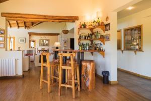 eine Küche und ein Wohnzimmer mit einer Bar mit Holzhockern in der Unterkunft Challhuaquen Lodge in Trevelín