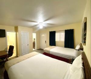 Habitación de hotel con 2 camas y ventilador de techo. en Europa Inn & Suites, en Desert Hot Springs