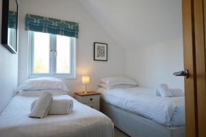 two twin beds in a room with a window at Lapwing Lake Lodge in Cirencester