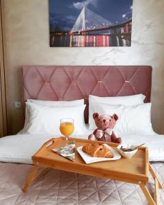 a teddy bear sitting on a bed with a tray of food at Apartman Planinski Kutak in Pale