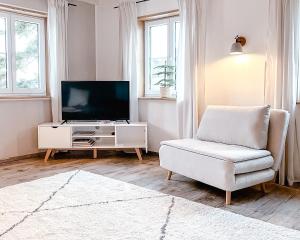 a living room with a chair and a television at FLYGGE Apartments in Altusried