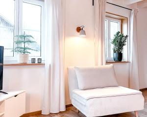 a white chair in a living room with a window at FLYGGE Apartments in Altusried