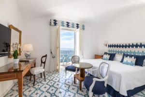 a hotel room with a bed and a desk and a window at Hotel Santa Caterina in Amalfi