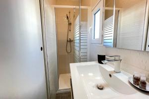 La salle de bains blanche est pourvue d'un lavabo et d'une douche. dans l'établissement Urban Chic By Anders - TerrasseWifiNetflixClim, à Marseille
