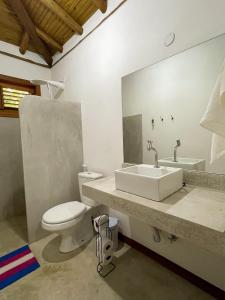 a bathroom with a sink and a toilet and a mirror at Vulva Caraíva Hostel e Pousada para Mulheres in Caraíva