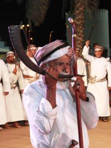 an older man holding a bow and arrow on a stage at Ibra Plaza Hotel in Ibrā +49 photos