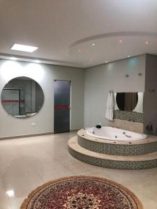 a large bathroom with a tub and a large mirror at Hotel Baeza in Goiatuba