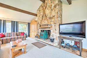 uma sala de estar com uma lareira de pedra e uma televisão de ecrã plano em Family Winter Retreat with Hot Tub 14 Mi to Slopes! em Whitingham