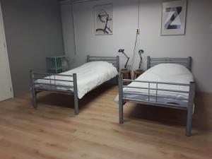 two beds in a room with wooden floors at Residentie De Hoek in Den Dungen