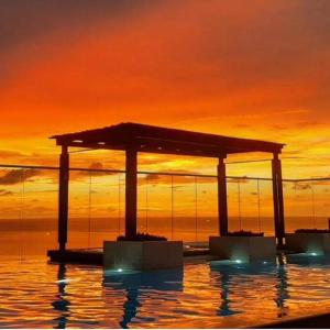 a pool of water with a sunset in the background at Reserva del Mar, Hermoso lugar de Descanso en Santa Marta in Gaira