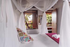 1 dormitorio con 1 cama blanca con dosel en Pousada Habitat Caraiva, en Caraíva