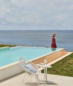 una mujer caminando en una cornisa junto a una piscina en Primera Línea de Mar con Yate "Estancia de Lujo" By Menorca Luxury Broker, en Cap d'en Font