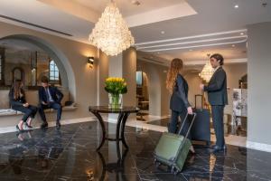 grupa ludzi czeka w holu z bagażem w obiekcie Hotel Astoria w Genui
