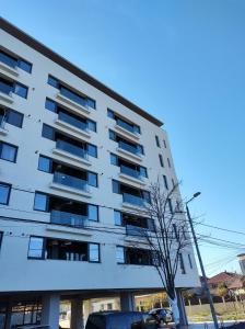 Un edificio de apartamentos con un árbol delante. en Retro Studio by the SEA, en Eforie Nord