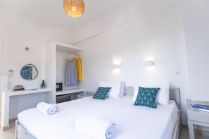 two beds in a bedroom with white walls and blue pillows at Akrotiri Hotel in Parikia