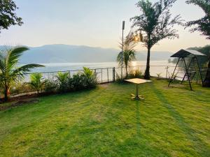 a picnic table in the grass next to the water at Lakeview Resort Lavasa in Lavasa