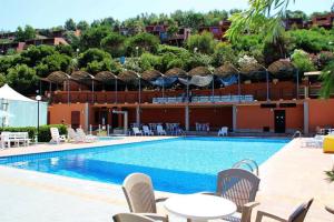 a swimming pool with tables and chairs next to a building at Turas Club Case Vacanze in Bosa