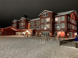 un gran edificio con mesas en la nieve por la noche en Stuga Sälen Kläppen 5 bäddar uthyres veckovis Söndag - Söndag, en Sälen