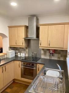 uma cozinha com armários de madeira e um lavatório em Glenbrae House 3 bedrooms near Nantwich with countryside views on private driveway em Nantwich