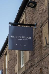 ein Schild, das an der Seite eines Gebäudes hängt in der Unterkunft The Smiddy Haugh in Auchterarder