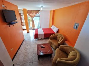 a room with a bed and two chairs and a tv at La Casa De Mi Sub in Puerto Baquerizo Moreno