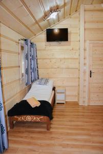 a small bedroom with a bed in a log cabin at Agroturystyka na starej drodze in Witów