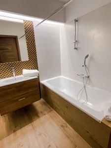 a bathroom with a tub and a sink and a mirror at Aparts Care Balic Polanki in Kołobrzeg