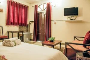 a bedroom with a bed and a tv and a chair at Dera Haveli- Heritage homestay in Gwalior