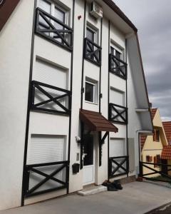 a white building with black doors and windows at Ajrin Apartman Kopaonik in Kopaonik