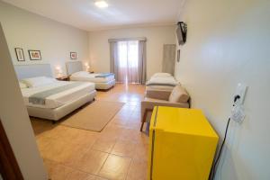 a hotel room with two beds and a yellow table at Pousada Girassol in Bonito