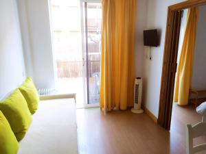 a living room with a couch and a window with yellow curtains at Blaupark apartamento vacacional con piscina y terraza en l'Estartit (Costa Brava) in L'Estartit