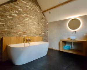 un bagno con ampia vasca bianca e lavandino di Nachtegael Hoekhuis, knusse woning met prachtig vergezicht a Kluisbergen