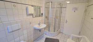 ein weißes Bad mit einem Waschbecken und einer Dusche in der Unterkunft Hotel Lamm in Stuttgart