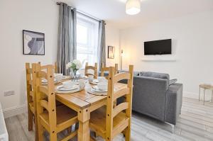 een eetkamer met een tafel en stoelen en een bank bij Caemawr Place - Stylish Home TV in Every Bedroom! in Swansea