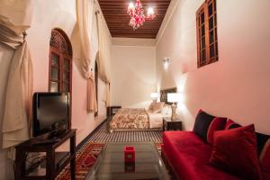 a living room with a red couch and a bed at Riad Noujoum Medina in Fès