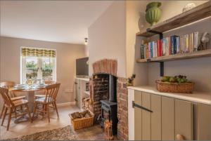 a living room with a brick fireplace and a table at Wishing Well Cottage in North Creake