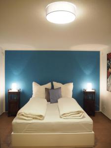 a bed with a blue wall and two night stands at Ferienwohnung am sonnigen Haimberg in Fulda