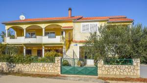 ein gelbes Haus mit einem Zaun davor in der Unterkunft Apartments Svarog in Biograd na Moru