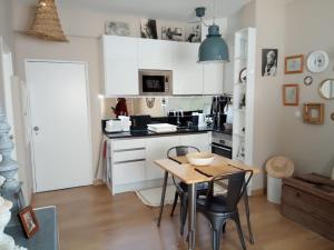 a kitchen with white cabinets and a table with chairs at Nora Velha T1 in Tavira