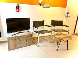 a room with three chairs and a flat screen tv at VIVA Hostel in Chur +20 photos