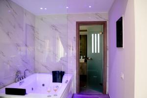 a white bathroom with a tub and a glass door at DAFNI LUXURY SUITES in Athens