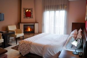 a bedroom with a white bed and a fireplace at Guesthouse Liogerma in Kato Loutraki