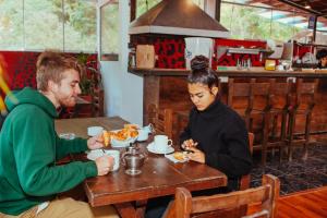 馬丘比丘的住宿－Nativus Hostel Machu Picchu，坐在餐桌旁吃食物的男人和女人