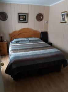 ein Schlafzimmer mit einem Bett mit einem Kopfteil aus Holz in der Unterkunft Gite la Maison Rochefort in Baie-Sainte-Catherine