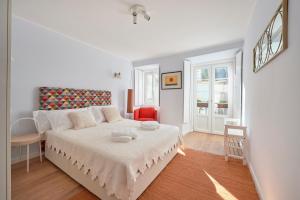 a white bedroom with a bed and a chair at Amazing Terrace and Riverview in Historical Lisbon in Lisbon