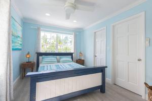 Dormitorio azul con cama y ventana en Harbour Mews - Oceanfront Townhouse, en Nassau