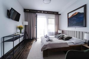 1 dormitorio con 1 cama y TV en IJG Imperial Apartamenty Krupówki, en Zakopane