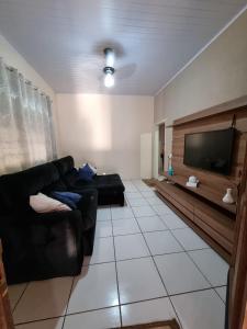 ein Wohnzimmer mit einem schwarzen Sofa und einem Flachbild-TV in der Unterkunft RECANTO ANDRADE in Olímpia