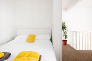 a bedroom with a white bed with yellow pillows at Modern, 2 Bdrm House Town Centre, North Laine Sleeps 6 in Brighton & Hove